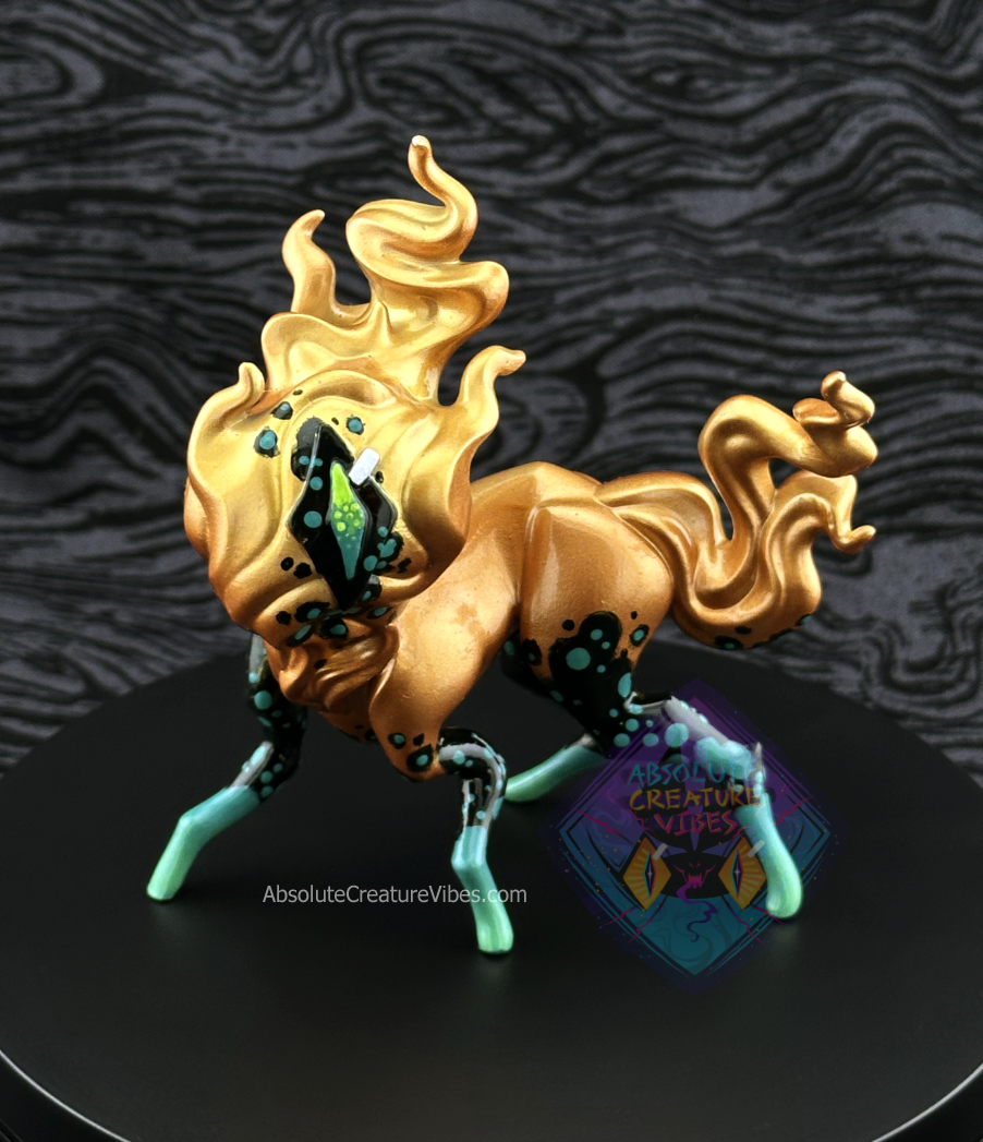 Four legged creature with flaming head and tail, one eye in the center. Copper body with black and green leg accents, black eye.
