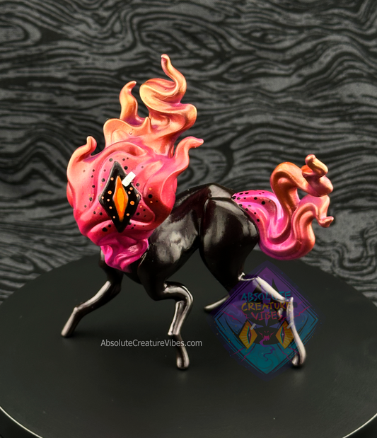 Four legged creature with flaming head and tail, one eye in the center. Pink, Copper, and Gold flame, black body, sclera; orange pupil.