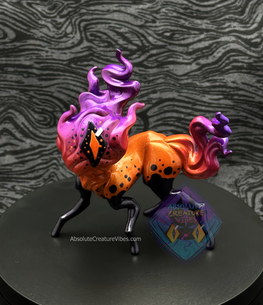 Four legged creature with flaming head and tail, one eye in the center. Bright orange body, orange, pink, purple flame, black legs, sclera, orange pupil.