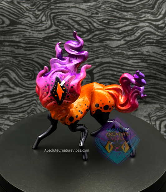 Four legged creature with flaming head and tail, one eye in the center. Bright orange body, orange, pink, purple flame, black legs, sclera, orange pupil.