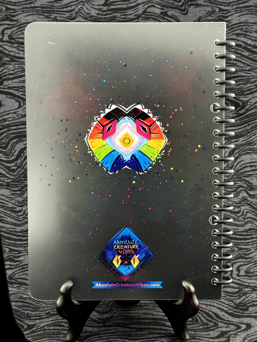 Back cover featuring rainbow progress pride flag frilled lizard face on a black background. Absolute Creature Vibes logo and web url listed at bottom.
