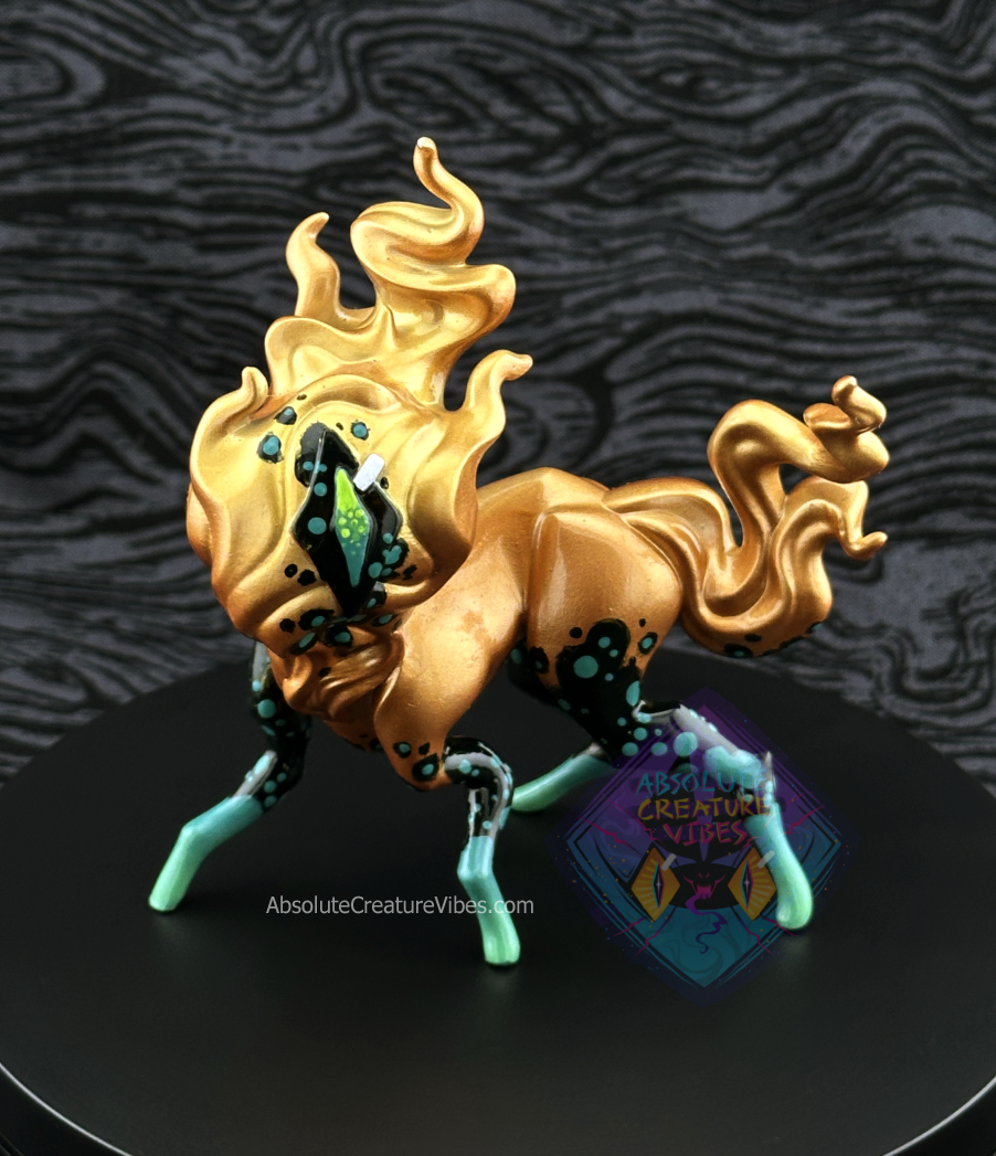 Four legged creature with flaming head and tail, one eye in the center. Copper body with black and green leg accents, black eye. 