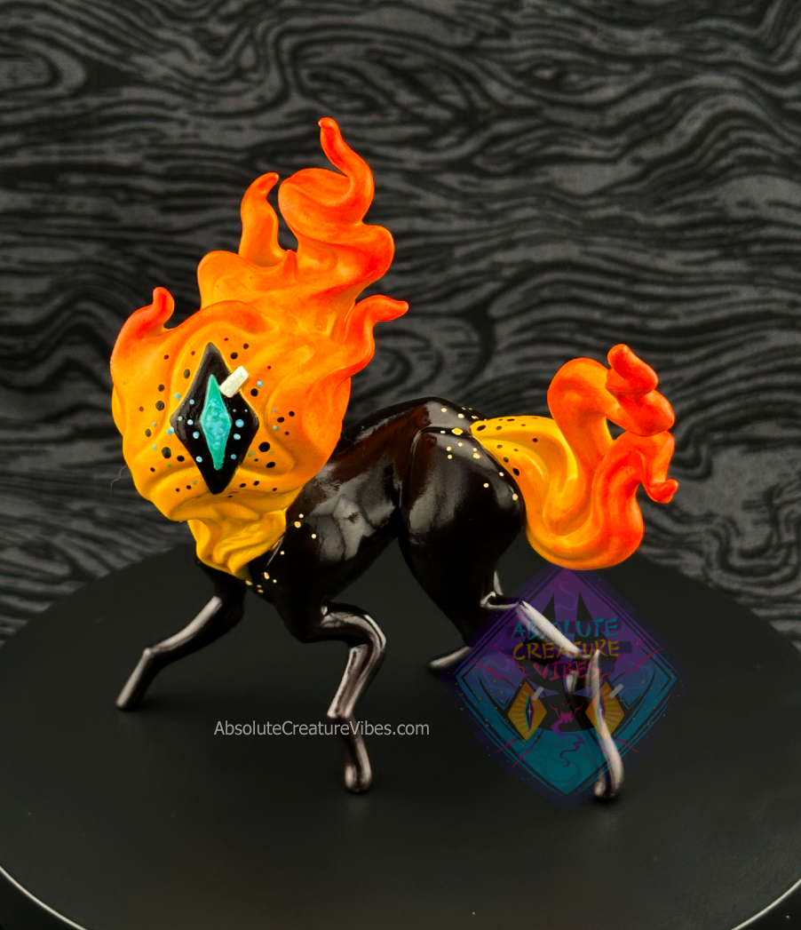 Four legged creature with flaming head and tail, one eye in the center. Yellow-orange flame, black sclera, body, aqua pupil. 