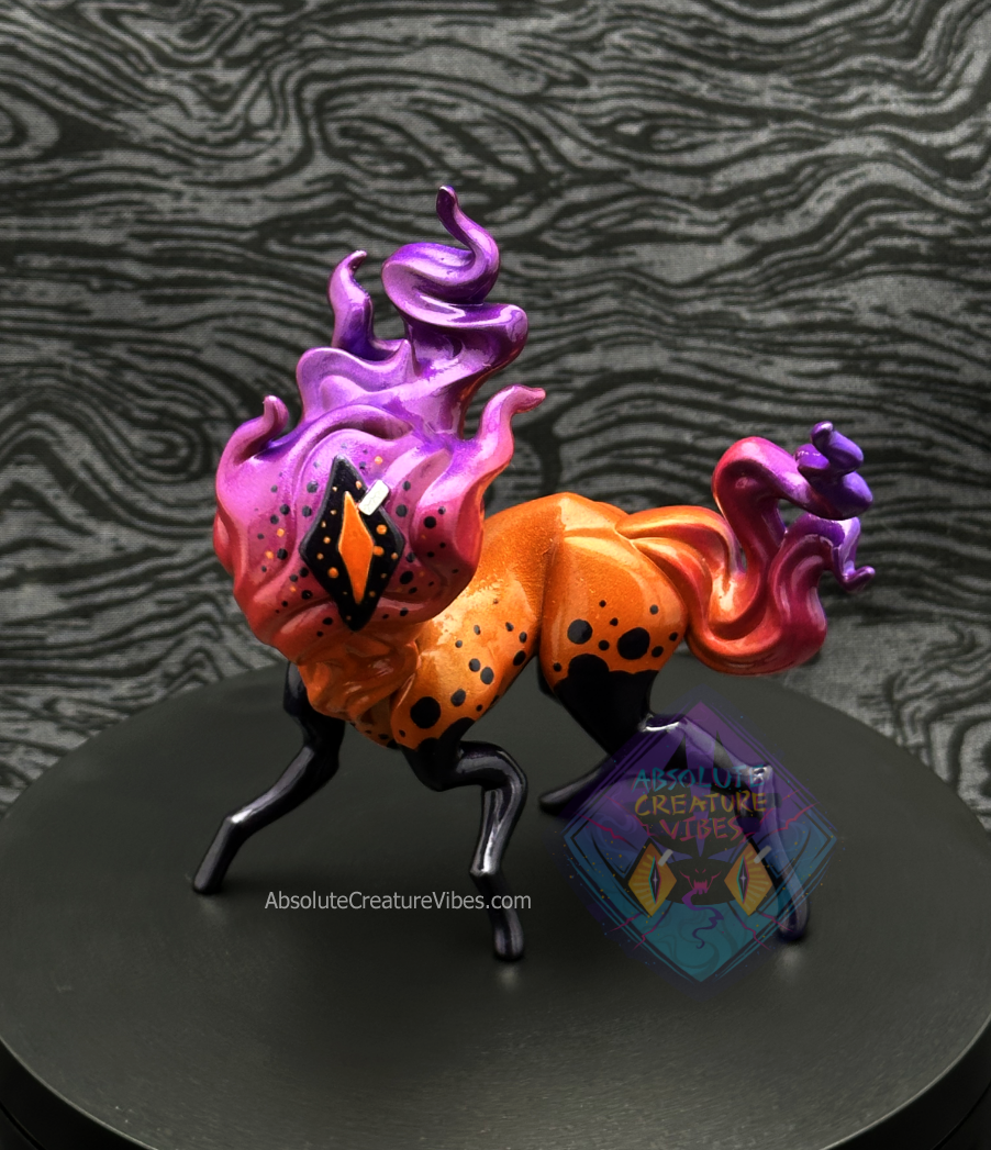 Four legged creature with flaming head and tail, one eye in the center. Bright orange body, orange, pink, purple flame, black legs, sclera, orange pupil. 